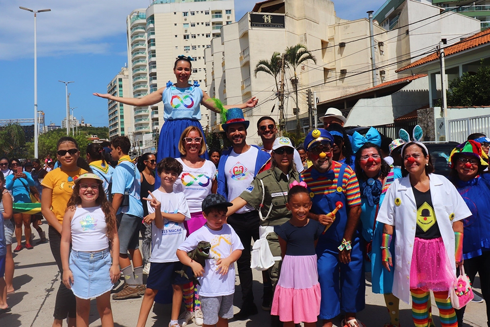 Um grupo de pessoas sorrindo vestidas com roupas e fantasias coloridos.